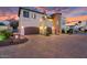 Elegant home exterior with a stone tower, two-car garage, and a spacious paver driveway at dusk at 3675 N 59Th Pl, Phoenix, AZ 85018