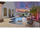 Luxury backyard pool with a sunning platform and waterfall, enhanced by ambient lighting and desert landscaping at 3675 N 59Th Pl, Phoenix, AZ 85018