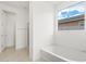 Bright bathroom with a soaking tub, tile flooring, and a large window at 37215 W Patterson St, Maricopa, AZ 85138