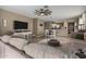 Spacious living room with a large sofa, entertainment center, and tile floors connected to dining and kitchen at 37384 W Prado St, Maricopa, AZ 85138
