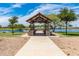 Picturesque park scene with a picnic shelter overlooking a tranquil lake and a bridge in the distance at 37384 W Prado St, Maricopa, AZ 85138