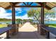 Scenic park view from a picnic shelter, showcasing a serene lake and walking path at 37384 W Prado St, Maricopa, AZ 85138