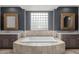 This bathroom showcases dual vanities, a soaking tub with travertine surround, and a glass block window at 3816 E Expedition Way, Phoenix, AZ 85050