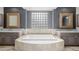 This bathroom showcases dual vanities, a soaking tub with travertine surround, and a glass block window at 3816 E Expedition Way, Phoenix, AZ 85050