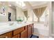 Well-lit bathroom with double sinks, wooden cabinets, large mirror, and a soaking tub at 3940 E Geronimo St, Gilbert, AZ 85295