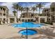 Community pool area featuring a jacuzzi, seating, and palm trees against a blue sky at 5303 N 7Th St # 118, Phoenix, AZ 85014