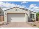 Close-up of a charming single-story home featuring a brick driveway and a two-car garage at 5312 W Hardtack Trl, Laveen, AZ 85339