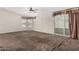 Spacious living room featuring brown carpet, a ceiling fan, and sliding glass doors to the patio at 5901 E Leonora St, Mesa, AZ 85215
