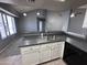 Kitchen featuring gray countertops, white cabinets, stainless steel sink, and open access to living room at 9209 N 59Th Ave # 206, Glendale, AZ 85302