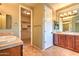 Well-lit bathroom featuring double sinks, cabinets, and a walk-in closet for ample storage at 9843 E Acacia Dr, Scottsdale, AZ 85260