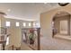 Bright hallway with staircase, wrought iron railing, and view to the kitchen area at 9843 E Acacia Dr, Scottsdale, AZ 85260