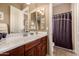 Well-lit bathroom featuring a cherrywood vanity, white countertop, and a shower with a privacy curtain at 1607 W Pearce Rd, Phoenix, AZ 85041