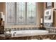 A luxurious soaking tub is surrounded by marble, while a decorative window lets in natural light at 1607 W Pearce Rd, Phoenix, AZ 85041