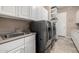 Bright laundry room with plenty of cabinets, a laundry sink, and washer and dryer at 1607 W Pearce Rd, Phoenix, AZ 85041