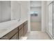Bright bathroom featuring double sinks, quartz countertop, and an adjacent walk-in shower at 17761 W Getty Dr, Goodyear, AZ 85338