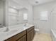 Bright bathroom featuring a double sink vanity, large mirror, and a shower-tub combination at 17761 W Getty Dr, Goodyear, AZ 85338