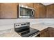 Close-up of a modern stainless steel stove and microwave with granite countertops and wood cabinets at 17761 W Getty Dr, Goodyear, AZ 85338