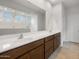 Bright bathroom featuring double sinks with wooden cabinets and a large mirror at 17776 W Getty Dr, Goodyear, AZ 85338