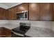 Close-up of kitchen appliances including a stainless steel microwave and electric range set against granite countertops and wooden cabinets at 17776 W Getty Dr, Goodyear, AZ 85338