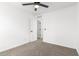 A bright bedroom featuring neutral carpeting, white walls, a ceiling fan, and paneled doors at 20116 W Monroe St, Buckeye, AZ 85326