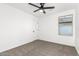 A bright bedroom featuring neutral carpeting, white walls, a ceiling fan, and a window at 20116 W Monroe St, Buckeye, AZ 85326