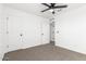 A bright bedroom featuring neutral carpeting, white walls, a ceiling fan, and paneled doors at 20116 W Monroe St, Buckeye, AZ 85326