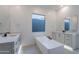 Bright bathroom boasts a modern tub, white cabinetry, dual sinks, and a large window for ample natural light at 21436 W Meadowbrook Ave, Buckeye, AZ 85396