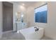 Modern bathroom with standalone tub, walk-in shower, bright finishes and a large picture window at 21436 W Meadowbrook Ave, Buckeye, AZ 85396