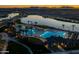 Aerial view of the community pool area at dusk with palm trees, lake, lounge chairs and a pool at 23162 E Canary Way, Queen Creek, AZ 85142