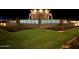 Nighttime view of the Barney Farms entrance, featuring a stone water fountain and manicured landscaping at 23162 E Canary Way, Queen Creek, AZ 85142