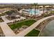 Aerial view showcases the community pool area with ample seating, lush landscaping, and a nearby pond at 23162 E Canary Way, Queen Creek, AZ 85142