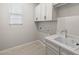 Functional laundry room featuring a white sink, white cabinets, and natural light at 23162 E Canary Way, Queen Creek, AZ 85142