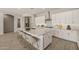 Well-designed kitchen includes a spacious island, granite counters, white cabinets, and bar stool seating at 23163 E Canary Way, Queen Creek, AZ 85142