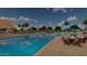Community pool with lounge chairs, tables, mature trees and sunshades with multiple swimmers enjoying the day at 23163 E Canary Way, Queen Creek, AZ 85142
