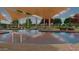 Community pool with lounge chairs, tables, mature trees and sunshades with multiple swimmers enjoying the day at 23163 E Canary Way, Queen Creek, AZ 85142
