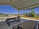 Covered picnic tables and benches near a green and yellow playset in a sunny community park at 24083 W Bowker St, Buckeye, AZ 85326