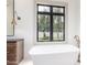 Bright bathroom with a modern tub, dark framed window, and a vanity with a sconce at 2505 E Lehi Rd # 16, Mesa, AZ 85213