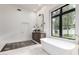 Bright bathroom featuring a modern tub, large window, vanity, and an area rug on tile floor at 2505 E Lehi Rd # 16, Mesa, AZ 85213