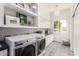 Bright laundry room with gray subway tiles, white cabinets and floating shelves, with a patterned floor at 2505 E Lehi Rd # 16, Mesa, AZ 85213
