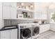 Well-lit laundry room featuring white cabinets, gray tiled backsplash, and modern washer and dryer at 2505 E Lehi Rd # 16, Mesa, AZ 85213