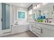 Bright bathroom with dual sinks, a soaking tub, a separate shower with blue tile accents, and large window at 2637 N 195Th Dr, Buckeye, AZ 85396