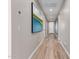 Hallway with neutral-toned walls, light wood-look flooring, and an eye-catching art piece at 2637 N 195Th Dr, Buckeye, AZ 85396