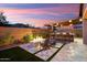 Relaxing backyard featuring a fire pit, built-in seating, and desert landscaping at sunset at 32268 N 133Rd Ln, Peoria, AZ 85383