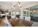 Elegant dining area with a wooden table, white chairs, and a modern chandelier, open to the kitchen and patio at 32268 N 133Rd Ln, Peoria, AZ 85383
