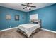 Bedroom with blue walls, ceiling fan, and framed posters at 44566 W High Desert Trl, Maricopa, AZ 85139
