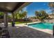 Inviting outdoor space with a refreshing pool, surrounded by a paved patio and lush landscaping at 44566 W High Desert Trl, Maricopa, AZ 85139