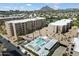 Aerial view of the community pool and apartment buildings in a lush neighborhood with a mountain backdrop at 7840 E Camelback Rd # 111, Scottsdale, AZ 85251