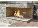Outdoor fireplace made of stone with a fire burning at 8220 E Mohawk Ln, Scottsdale, AZ 85255
