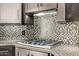 Kitchen with mosaic backsplash, granite counters, and stainless steel gas cooktop at 8220 E Mohawk Ln, Scottsdale, AZ 85255