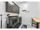 Well-lit laundry room with front load washer and dryer, dark cabinets, and decorative laundry-themed wall art at 830 E Buist Ave, Phoenix, AZ 85042
